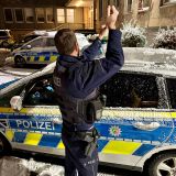 Polizeibeamter fegt Schnee vom Streifenwagen