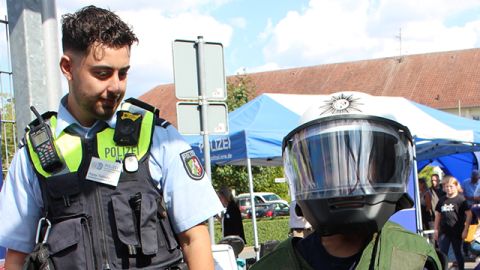 zwei Personen, ein uniformierter Polizeibeamter und ein Besucher in Schutzausstattung